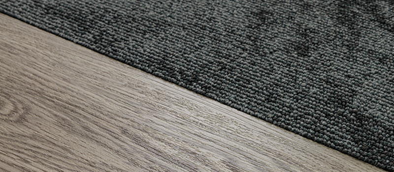 Dark carpet over light brown vinyl plank flooring