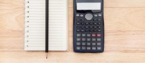 blank notebook and calculator on a wooden surface